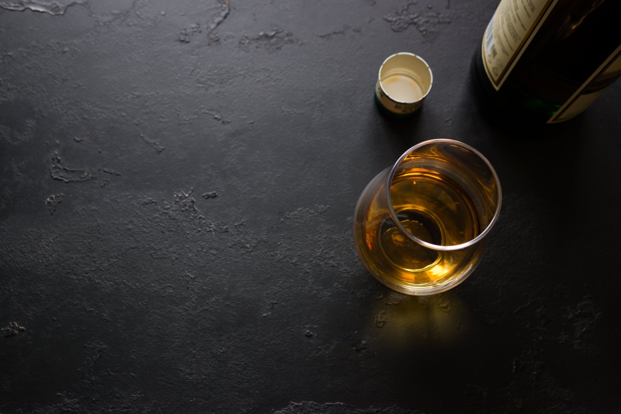 Glass of Whisky on a Table Next to an Open Bottle of Whisky